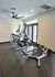 Modern fitness room with sleek elliptical machines and a versatile workout bench, illuminated by natural light from large windows.