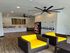Modern laundry room with sleek appliances, vibrant yellow seating, and contemporary decor.