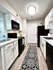 Modern kitchen with sleek black and white appliances, elegant cabinetry, and stylish patterned floor runner.