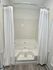 Luxurious bathroom with elegant corner soaking tub, accented by pristine white tiles and sleek flooring for a spa-like retreat.
