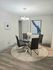Elegant dining area with a modern glass table, chic gray chairs, and stylish artwork creating a cozy atmosphere.