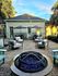 Charming outdoor patio with modern seating, elegant fire pit, and shaded tables, surrounded by lush greenery and a cozy bungalow backdrop.