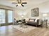 Bright and inviting living room with sleek flooring, elegant gray sofa, and modern decor, enhanced by natural light from large windows.