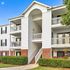 Charming apartment building with classic white siding, inviting balconies, and a well-manicured landscape offering serene living spaces.