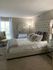 Elegant bedroom with luxurious tufted headboard, plush bedding, and modern mirrored nightstand creates a cozy and sophisticated retreat.