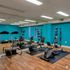 Modern fitness center with vibrant teal walls, equipped with a treadmill, exercise bike, rowing machine, and colorful exercise balls, complemented by a wall-length mirror.