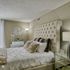 Elegant bedroom with a plush tufted headboard, cozy bedding, and mirrored furniture for a luxurious touch.
