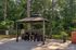 Charming outdoor gazebo with sleek furniture, surrounded by lush greenery, perfect for relaxing or entertaining.