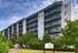 Elegant modern apartment building with spacious balconies, nestled amidst lush greenery and vibrant landscaping.