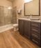 Elegant bathroom featuring a sleek glass shower, stylish granite countertops, and warm wood flooring.