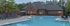 Inviting apartment complex with a sparkling blue pool, surrounded by lounge chairs and lush greenery, perfect for relaxation and leisure.