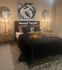 Chic and cozy bedroom with modern decor, featuring a plush bed adorned with decorative pillows, stylish side tables with warm lighting, abstract art, and a touch of nature with potted plants.