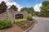 Welcoming entrance of The Huntley Apartment Homes with elegant stonework and vibrant landscaping under a bright blue sky.