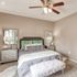 Cozy bedroom with elegant d&eacute;cor, featuring a plush bed with decorative pillows, chic mirrored nightstands, and a stylish ceiling fan.