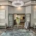 Elegant lobby featuring a crystal chandelier, welcoming decor with floral centerpiece on glass table, and inviting entrance to a stylish interior.