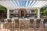 Charming apartment complex features inviting outdoor bar area with stylish seating under a sunlit pergola, offering perfect space for relaxation and social gatherings.