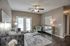 Elegant living room with modern decor, featuring a plush gray sofa, mirrored coffee table, and chic lighting, with doors opening to a cozy outdoor space.