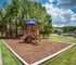 Charming community playground with vibrant equipment surrounded by lush greenery and residential buildings perfect for family living.