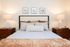 Elegant bedroom with a comfortable bed, stylish lamps, and framed artwork creating a cozy and inviting atmosphere.