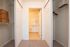 Spacious walk-through closet leading to a bright bathroom, featuring ample shelving and elegant storage solutions.