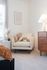 Cozy reading nook featuring a plush armchair with a decorative pillow, warm lighting from a stylish lamp, and elegant wall art.