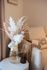 Chic living space featuring a cozy, neutral-toned sofa, elegant dried flower arrangement, and decorative throw.
