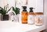 Elegant bathroom vanity with chic hand soap bottles, cotton balls, and ear swabs, accented by lush greenery.