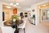 Inviting open-concept living area with elegant dining table, modern kitchen, cozy fireplace, and abundant natural light.