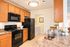 Inviting kitchen with modern black appliances, warm wood cabinetry, and elegant countertops, creating a cozy and functional cooking space.