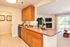 Inviting open-concept kitchen and living area featuring warm wood cabinets, a cozy fireplace, and a scenic view through large windows.
