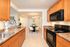 Inviting open-plan kitchen and dining area with modern appliances, elegant lighting, and warm wood cabinetry.