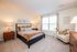Bright and inviting bedroom with elegant decor, featuring a comfortable bed, stylish side tables, and a large window offering plenty of natural light.