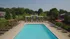 Luxury apartment complex featuring a pristine outdoor pool with comfortable loungers, surrounded by lush greenery and pergolas for shaded relaxation.