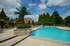 Luxurious outdoor pool area with sparkling blue water, surrounded by lush greenery and elegant lounge chairs beneath vibrant umbrellas.