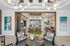 Contemporary living area with chic decor, featuring modern chandeliers, vibrant artwork, and a cozy seating arrangement, offering a glimpse of inviting outdoor views.