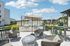 Inviting outdoor patio featuring modern barbecue grills, stylish seating, and lush greenery under a clear sky.