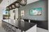 Modern apartment amenity area featuring a sleek long table with stylish pendant lighting, elegant backsplash with vibrant art, and scenic outdoor view.