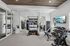 Modern and spacious apartment gym featuring a variety of fitness equipment, including a punching bag, free weights, and cardio machines, complemented by natural light and elegant decor.
