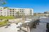 Modern apartment complex with spacious outdoor seating, lush greenery, and inviting poolside area under a clear blue sky.