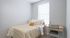 Cozy bedroom featuring a stylish bed with neutral bedding and a modern desk by the window, perfect for a serene workspace.