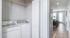 Bright apartment hallway featuring an elegant in-unit laundry area, leading to a stylish living room with natural light.