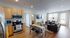 Modern open-concept living space showcasing a sleek kitchen with stainless steel appliances, a cozy dining area, and a stylish living room with large windows.