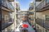 Chic apartment complex courtyard with modern balconies, vibrant red umbrellas, and a stylish outdoor seating area.