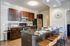 Modern kitchen with dark wood cabinets, stainless steel appliances, and a sleek island with bar seating.