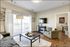 Bright and inviting living room with stylish decor, featuring a cozy green armchair, modern coffee table, and large windows with ample natural light.
