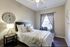 Inviting bedroom featuring elegant decor, a cozy wooden bed, and ample natural light from a large window.