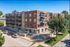 Charming brick apartment building with modern balconies and large windows, nestled on a tree-lined street.