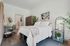 Modern bedroom with stylish decor, featuring a cozy bed, chic artwork, and lush greenery for a serene ambiance.