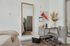 Chic bedroom corner with modern desk setup, cozy textiles, and a large decorative mirror adding elegance and style.