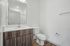 Sleek modern bathroom with elegant fixtures, featuring a stylish wooden vanity and pristine white walls.